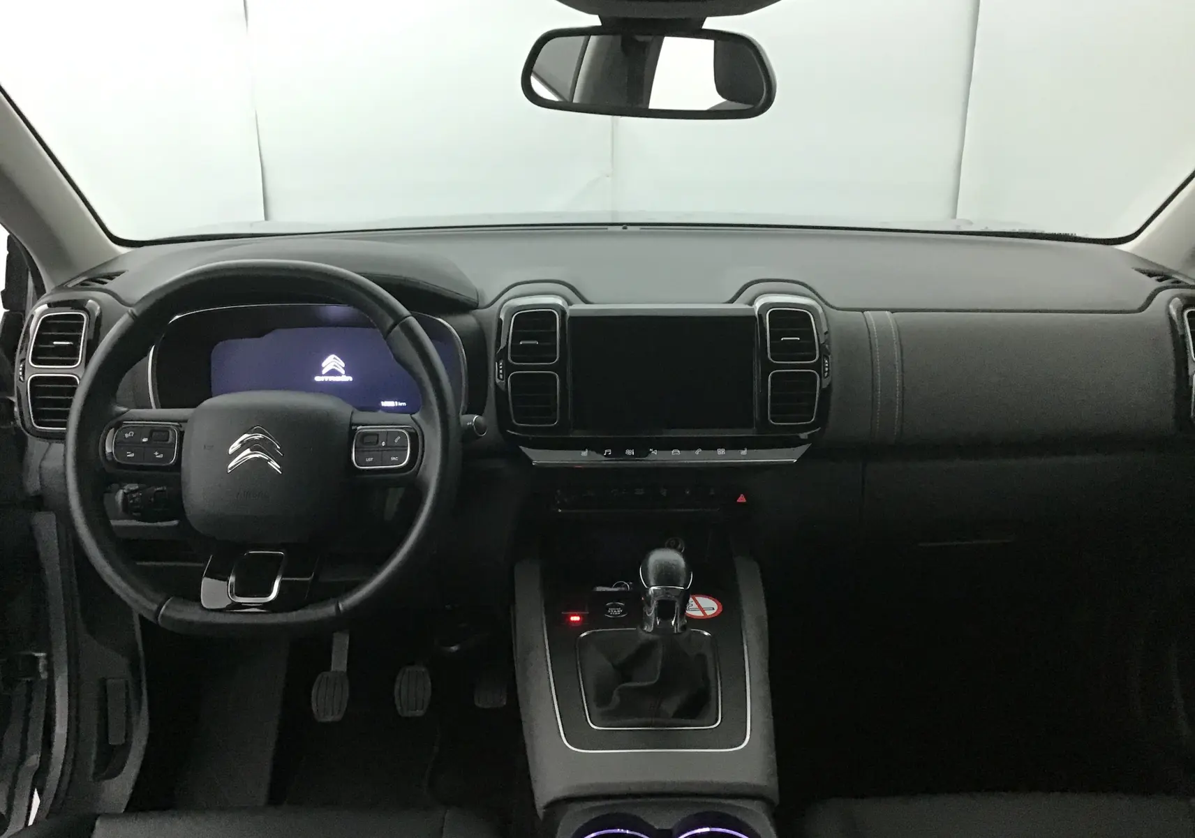 Vue intérieure frontale du tableau de bord et volant du Citroën C5 Aircross 2021 avec boîte manuelle et écran tactile éteint.