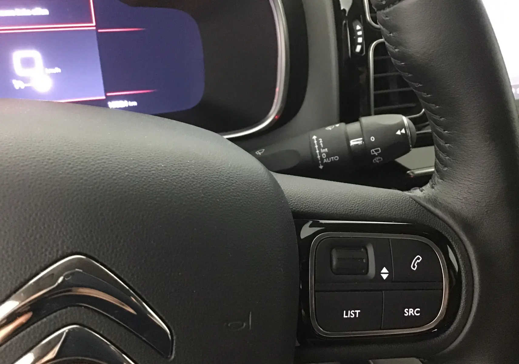 Gros plan sur le volant cuir noir du Citroën C5 Aircross 2021 avec commandes audio et tableau de bord numérique.