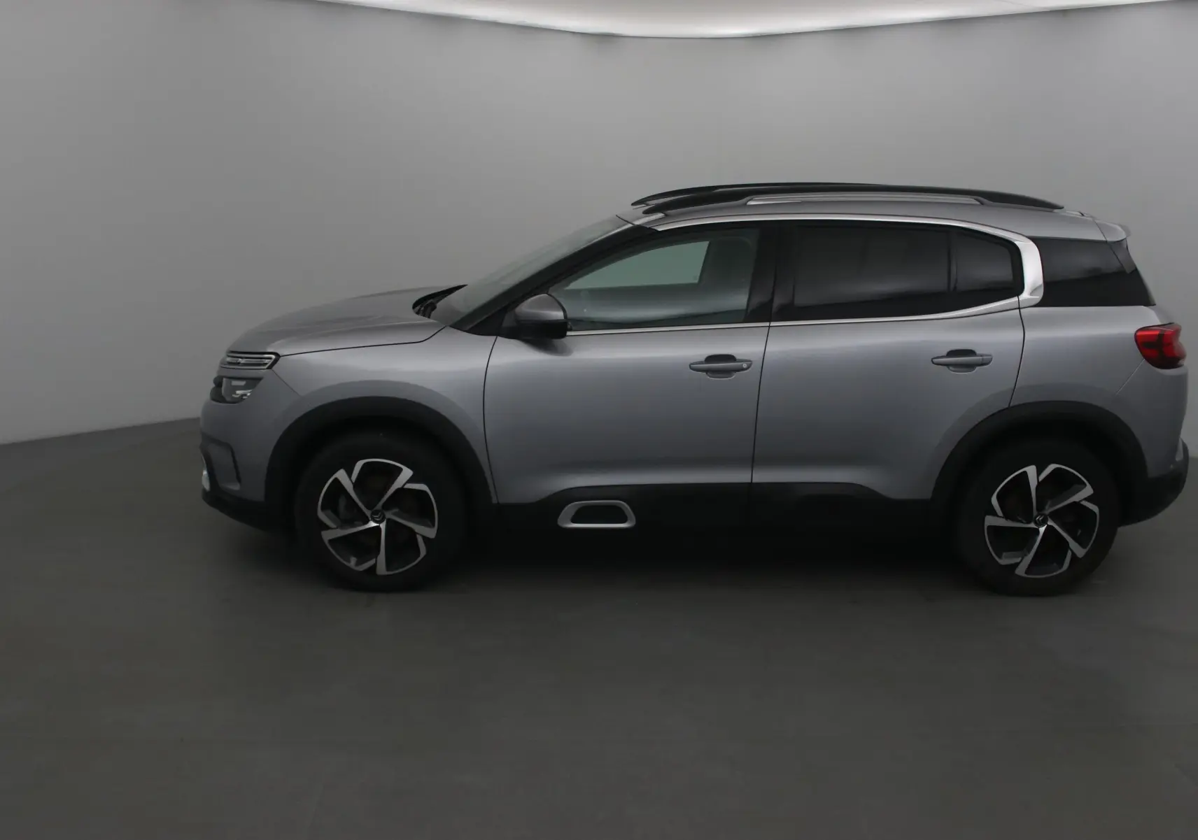 Profil côté gauche du Citroën C5 Aircross gris Artense 2021 avec jantes alliage et barres de toit noires.