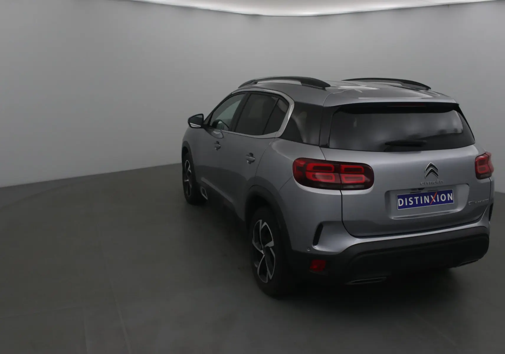 Vue 3/4 arrière droite d'un Citroën C5 Aircross gris Artense avec vitres teintées et jantes noires.