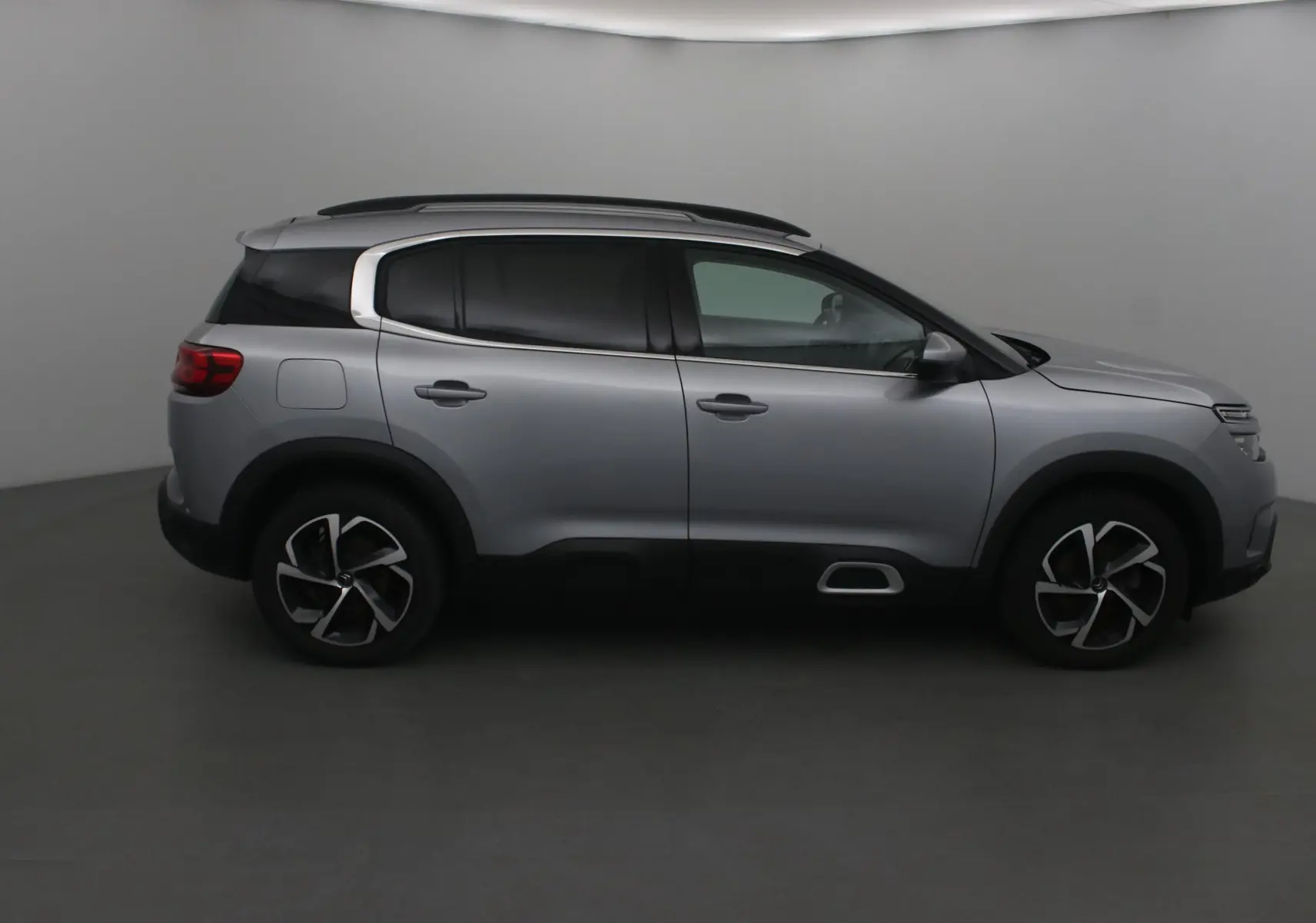 Profil côté droit du Citroën C5 Aircross gris Artense avec jantes alliage et barres de toit visibles.