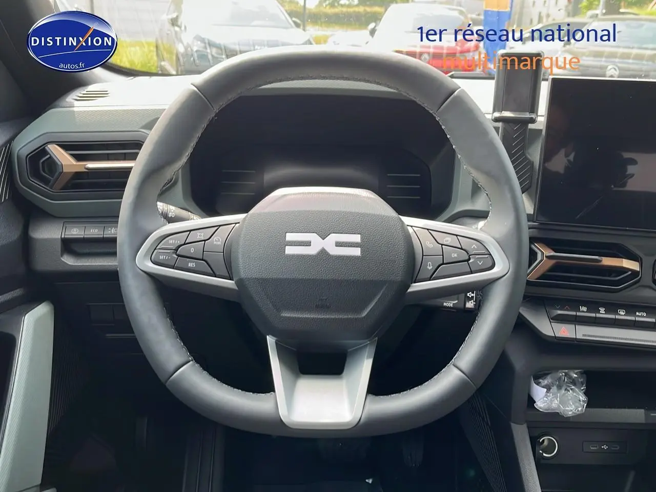 Vue centrée sur le volant multifonction noir du Dacia Duster 2025 avec tableau de bord et écran tactile visibles.