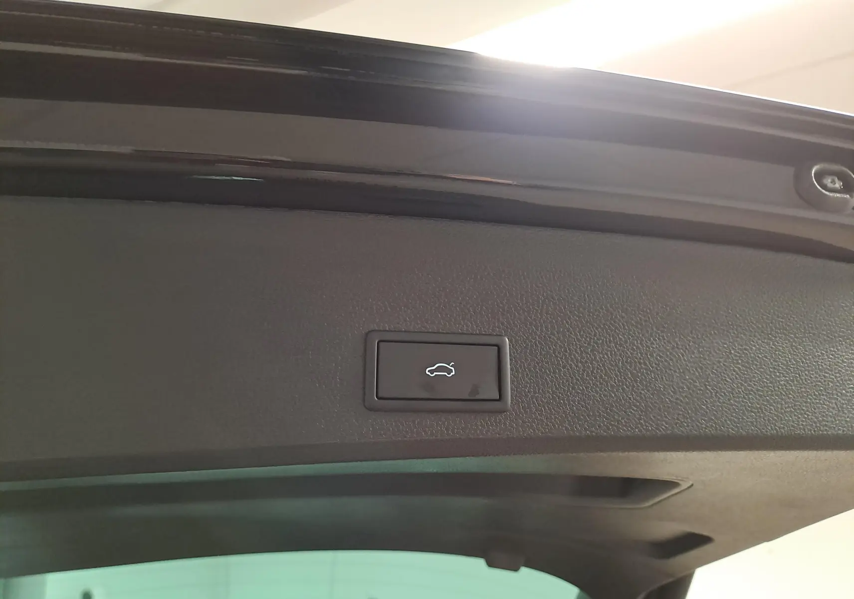 Bouton d'ouverture électrique du hayon sur la partie intérieure du coffre d'un SEAT Ateca Noir Minuit, vue rapprochée.