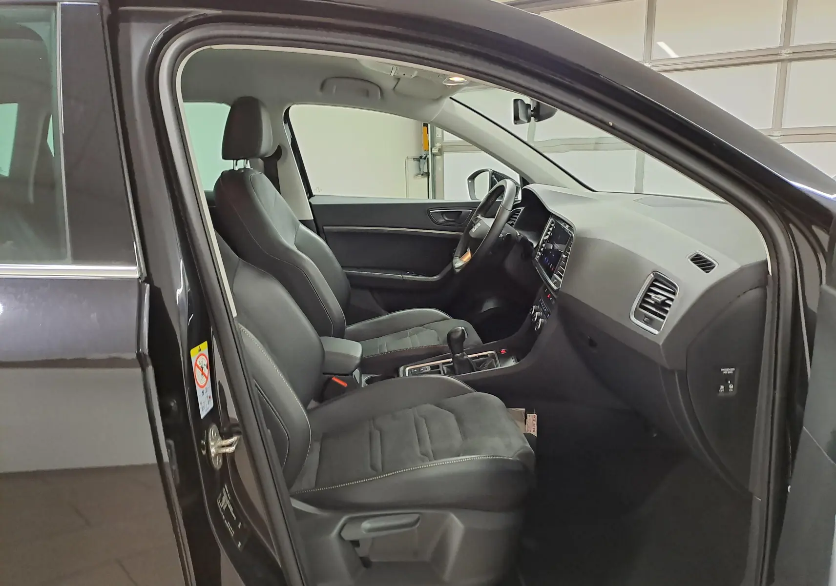 Vue intérieure côté conducteur du SEAT Ateca 2023 noir minuit, avec sellerie suédine noire et tableau de bord noir Titane.