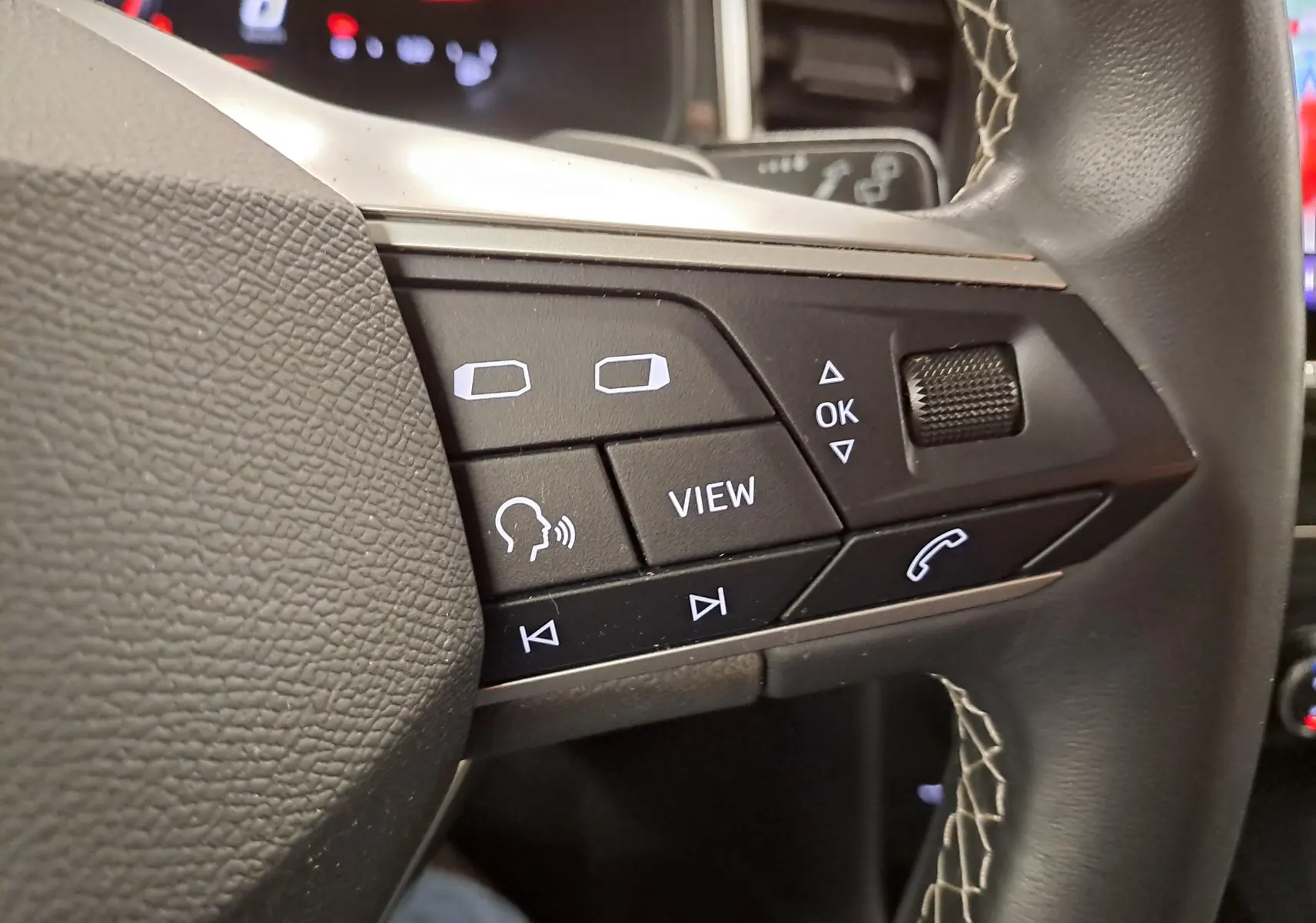 Gros plan sur les commandes multifonctions noires à gauche du volant du SEAT Ateca 2023 Noir Minuit.