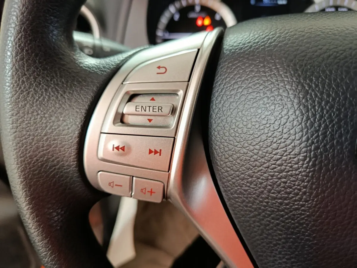 Gros plan sur le volant noir multifonctions du Nissan Navara 2018, avec boutons de contrôle argentés et affichage partiel du tableau de bord.