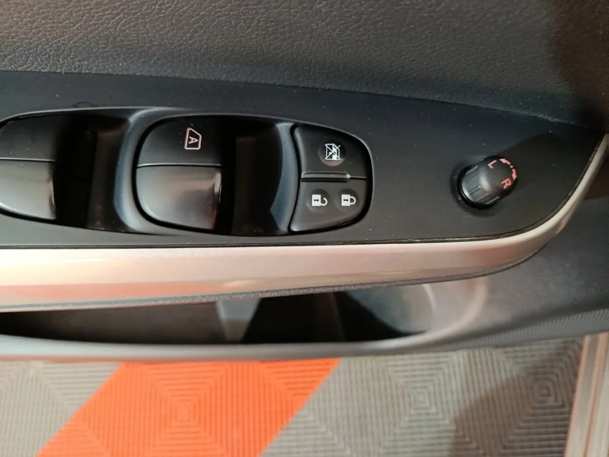 Gros plan sur la commande des vitres et rétroviseurs côté conducteur du Nissan Navara gris clair, intérieur noir.