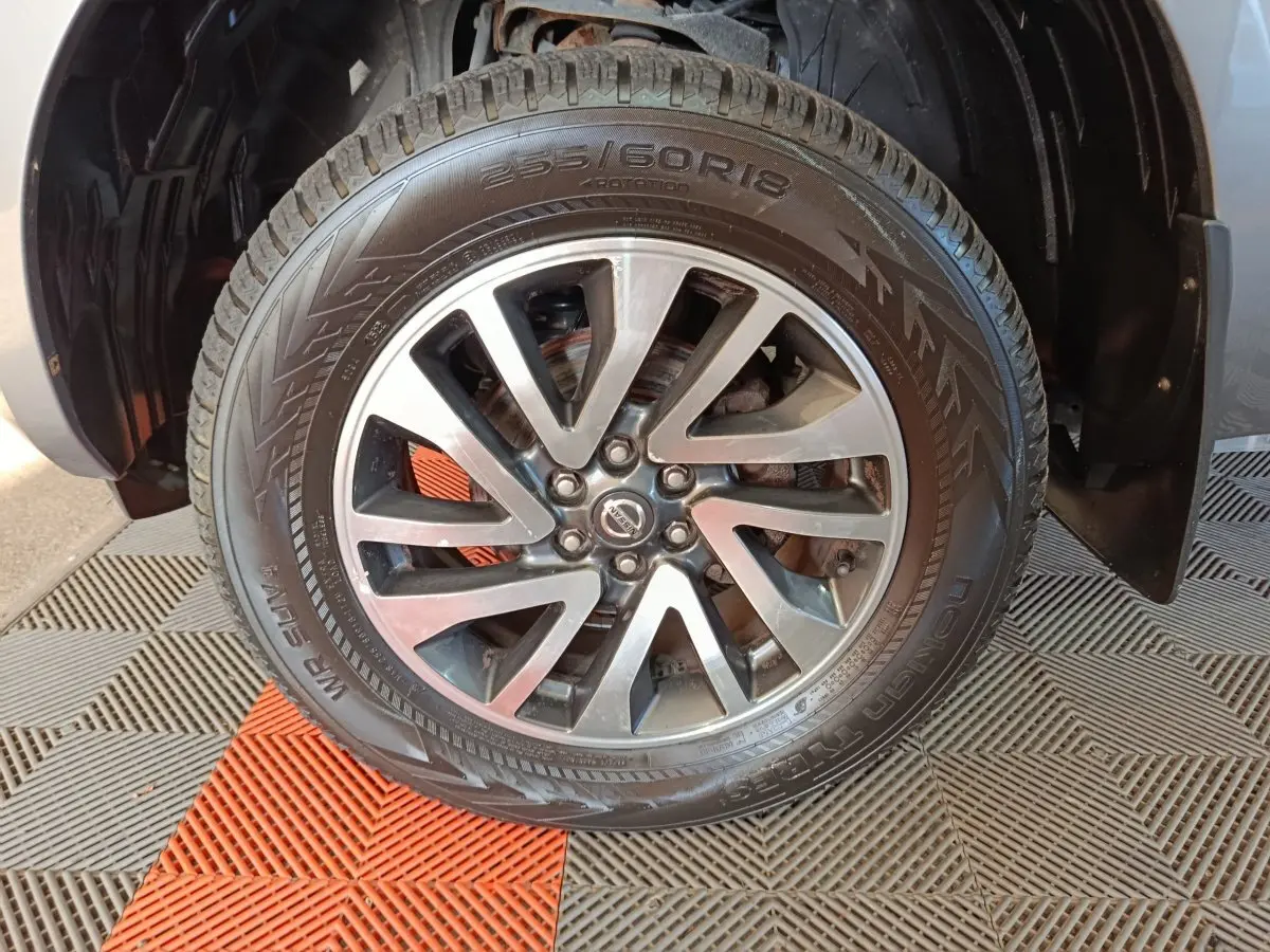 Gros plan sur la roue avant droite du Nissan Navara gris clair, mettant en valeur la jante alliage et le pneu Nokian.