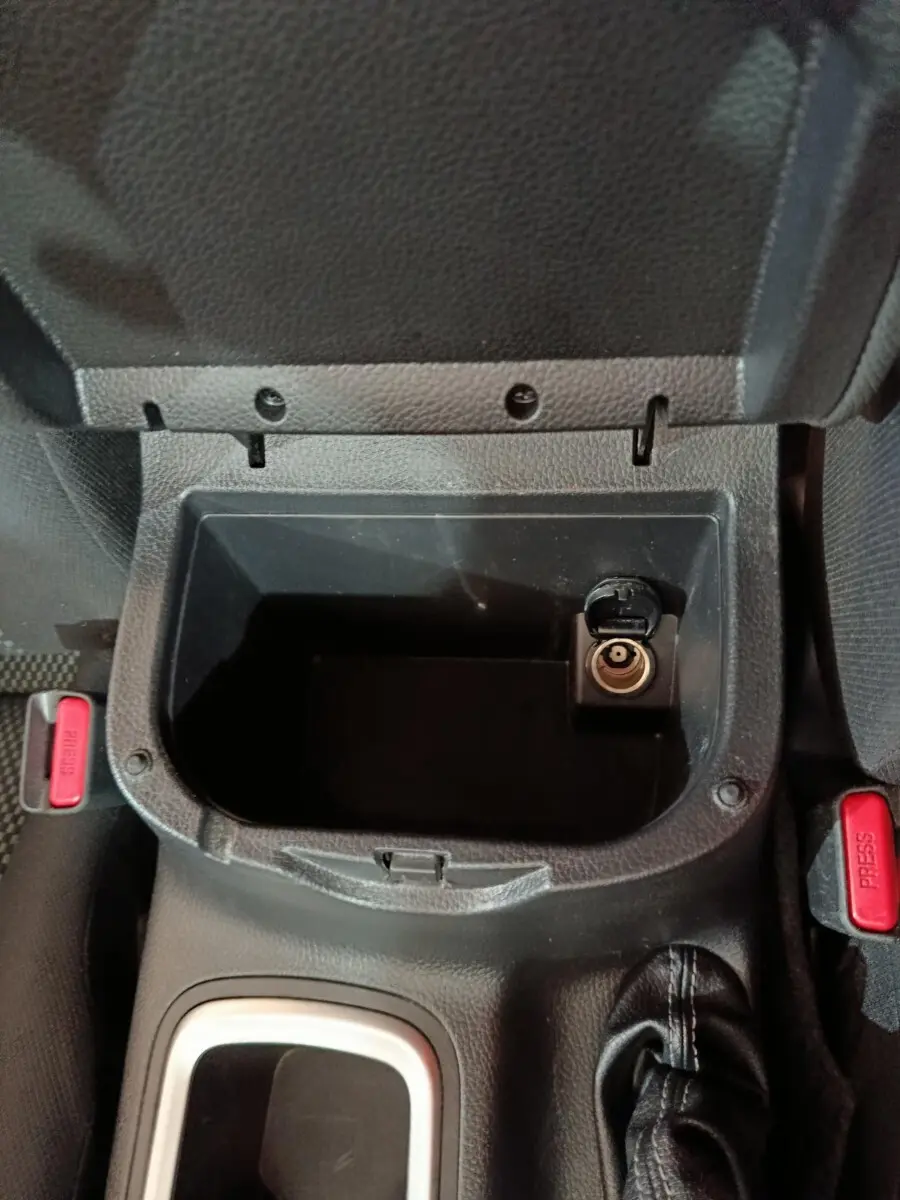 Vue rapprochée de la console centrale noire du Nissan Navara avec prise allume-cigare et bouton de frein à main visible.