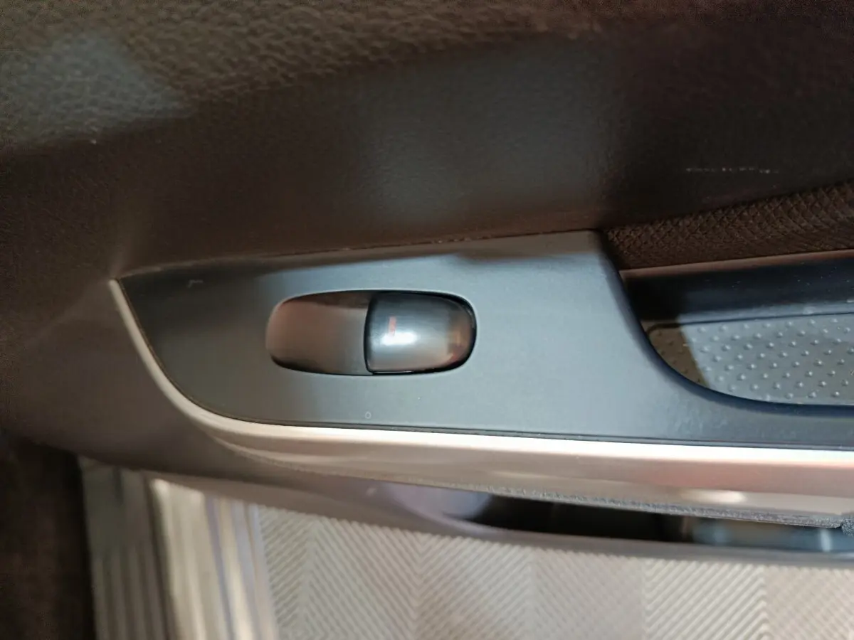 Gros plan sur le bouton de verrouillage de porte intérieur noir dans un Nissan Navara gris clair, version Double-Cab 2018.