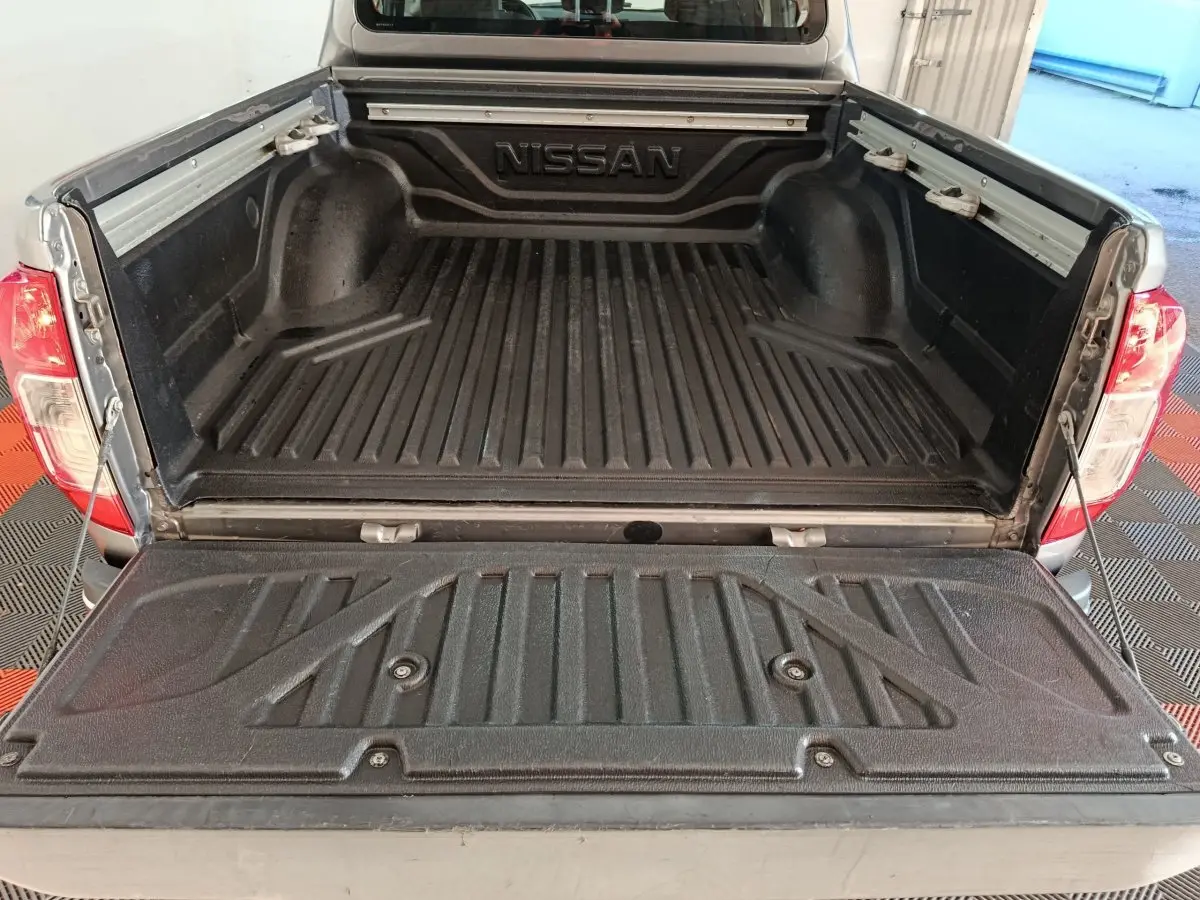 Vue arrière du pick-up Nissan Navara gris clair 2018 avec benne ouverte et revêtement noir antidérapant.