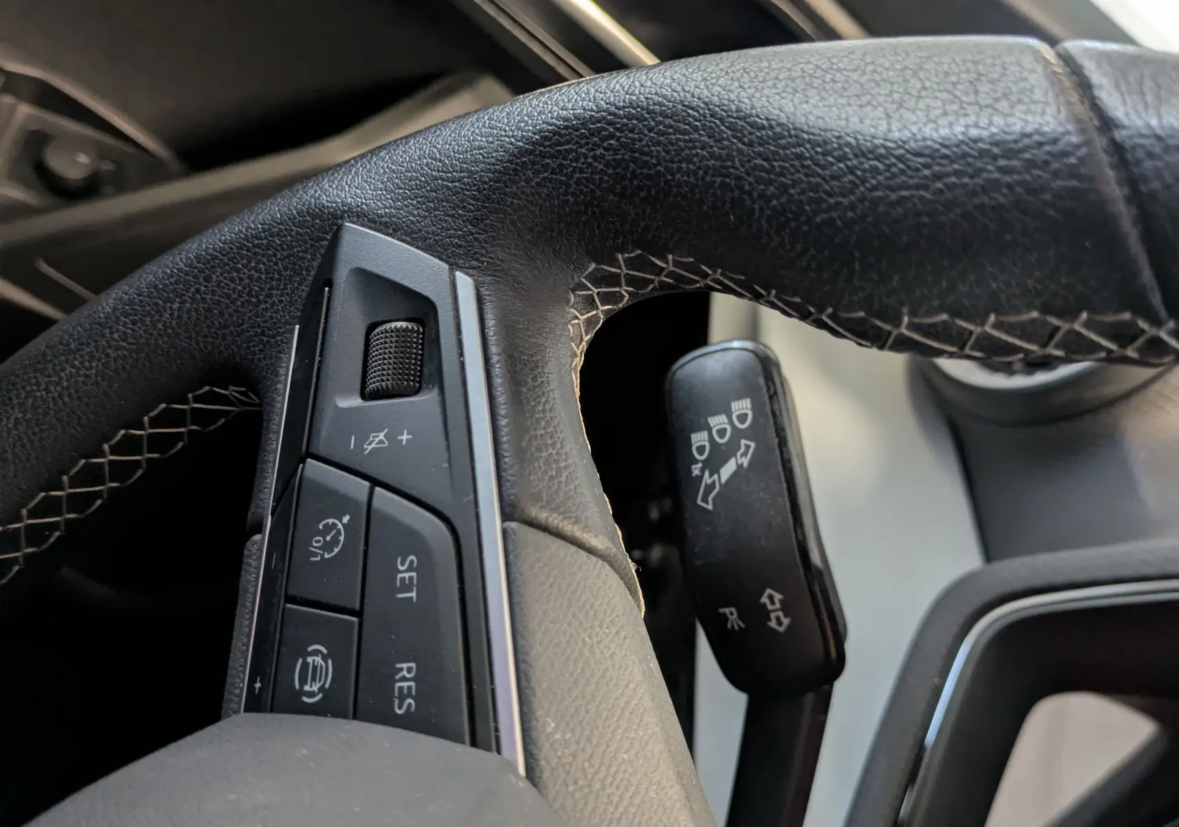 Gros plan sur le volant en cuir noir avec commandes intégrées côté gauche dans l’habitacle d’une SEAT Ibiza blanche.