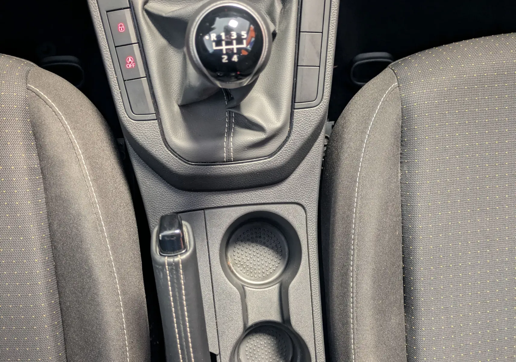 Vue plongeante sur la console centrale intérieure de la SEAT Ibiza blanche, mettant en valeur la boîte manuelle et les sièges gris.