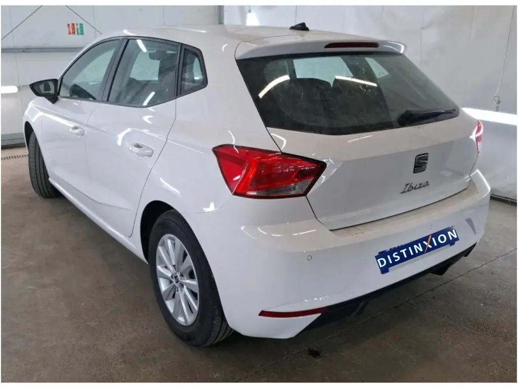 Vue de profil côté gauche d'une SEAT Ibiza blanche 5 portes, berline essence 2022, en intérieur showroom.
