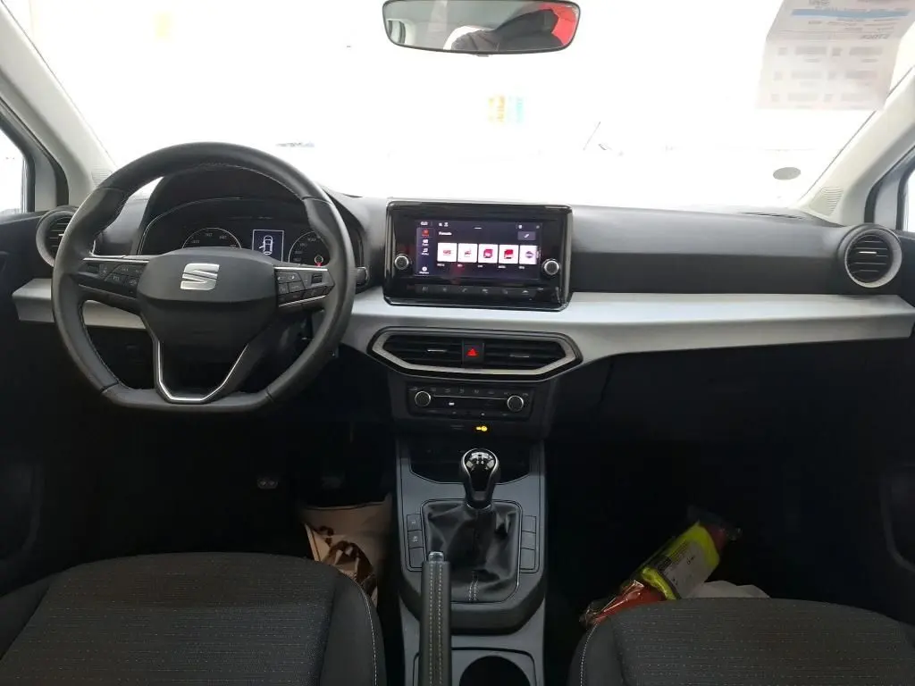 Vue plongeante sur le coffre ouvert d'une SEAT Ibiza blanche 5 portes, montrant un espace de rangement vide et propre.