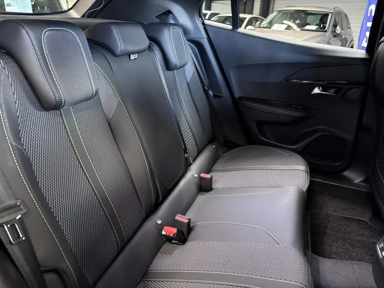Vue latérale droite de la banquette arrière noire avec surpiqûres vertes du Peugeot 2008 1.2i Hybrid GT 2026.