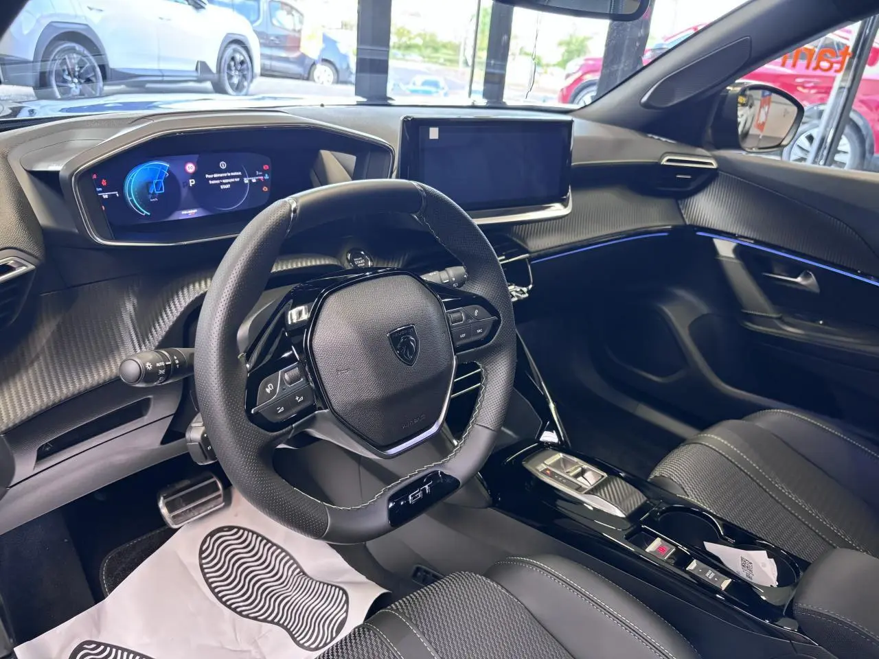 Vue intérieure côté conducteur du Peugeot 2008 GT 2026, tableau de bord noir avec écran tactile et volant compact cuir.
