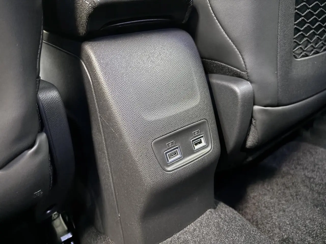 Prise USB type C et USB type A pour passagers arrière sur console centrale noire du Peugeot 2008 GT hybride 2026.