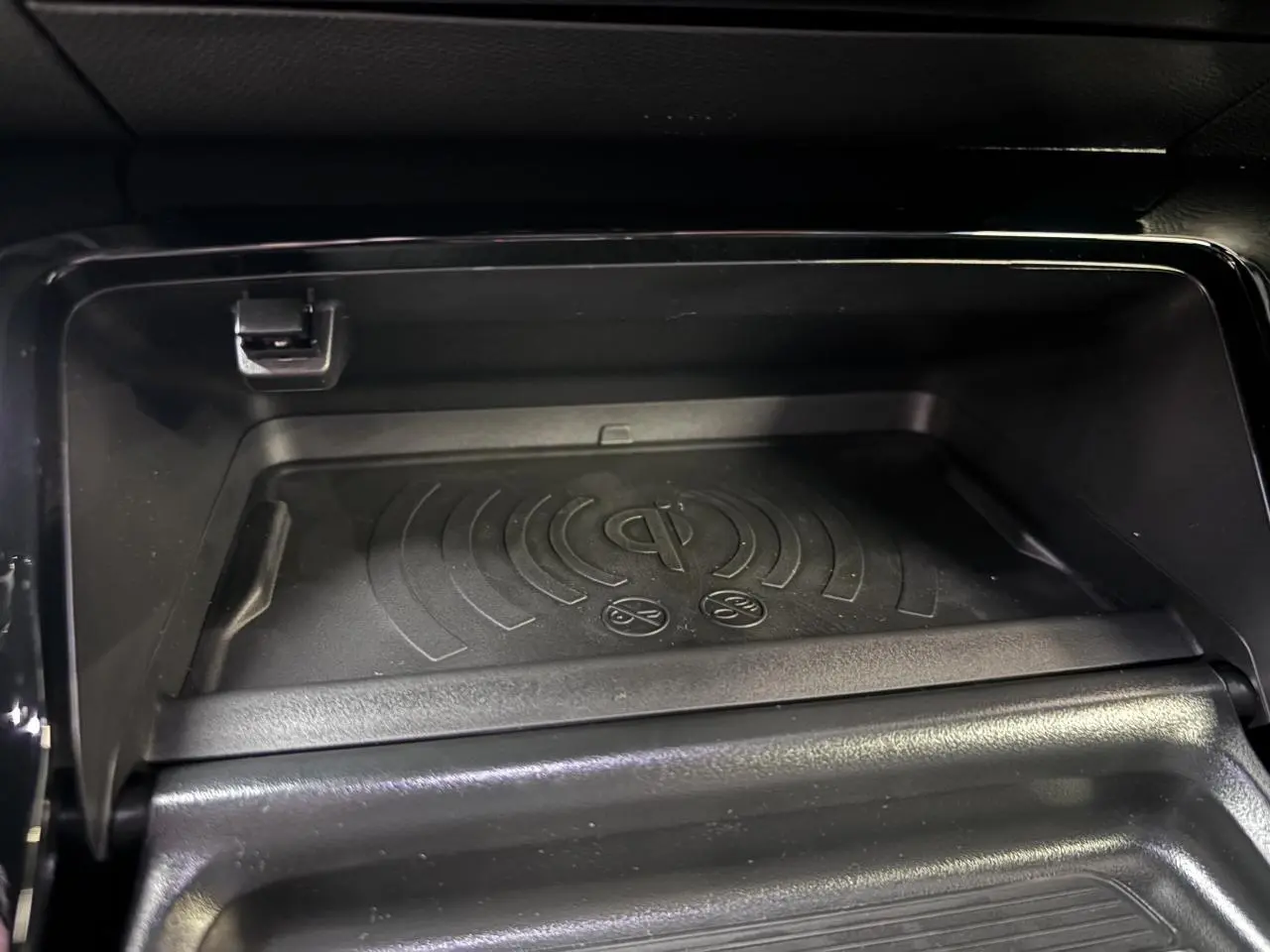 Gros plan sur le chargeur à induction noir dans la console centrale du Peugeot 2008 1.2i Hybrid GT 2026.