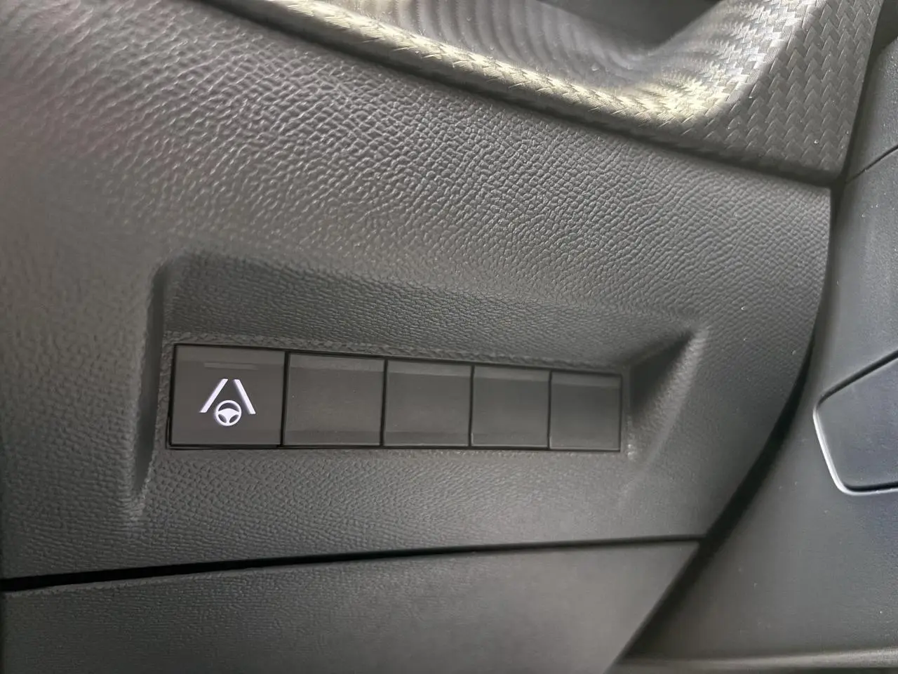 Gros plan sur bouton d’aide au maintien dans la file sur tableau de bord noir du Peugeot 2008 hybride 2026.