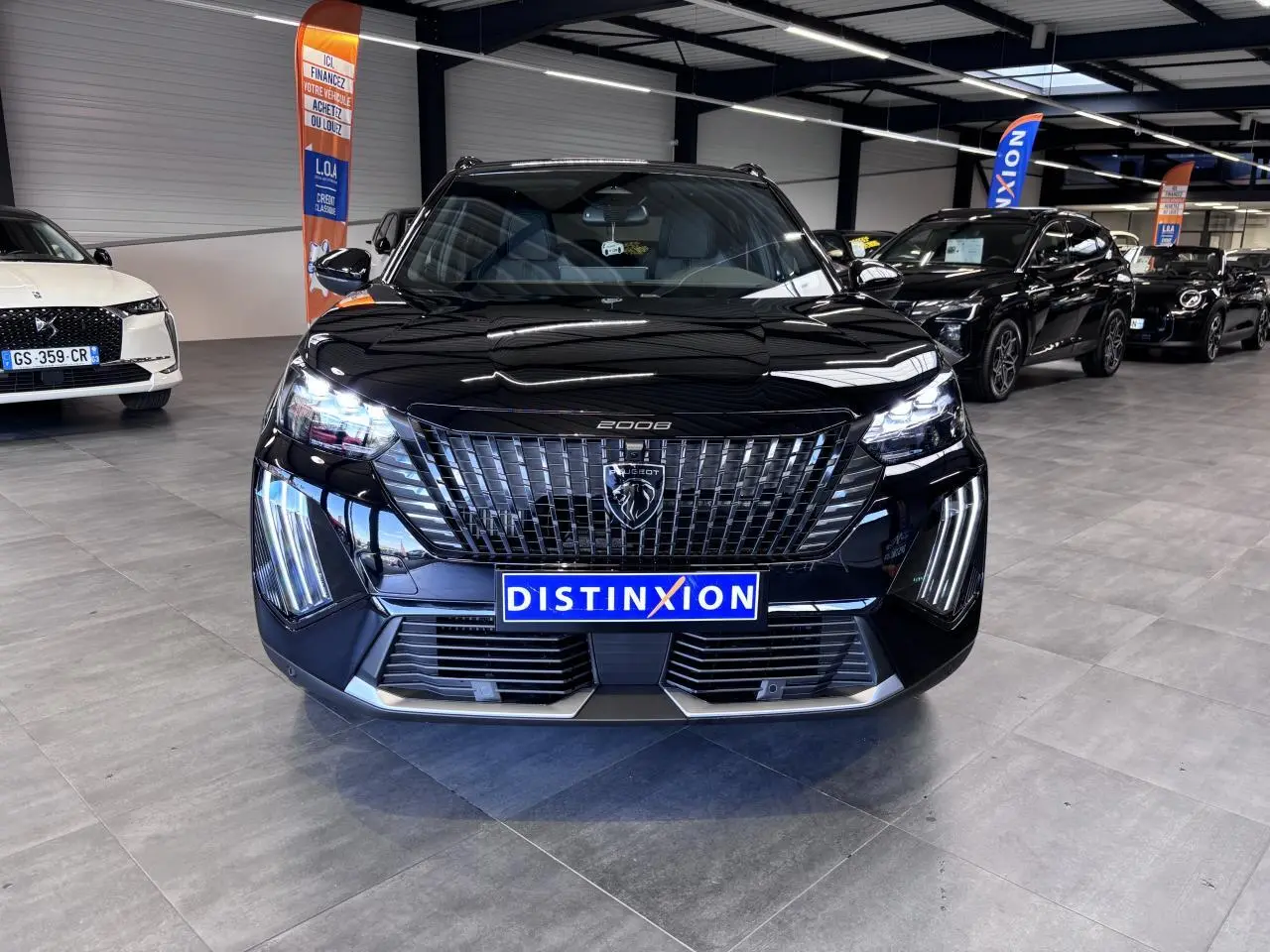 Vue avant d'un Peugeot 2008 noir brillant avec calandre verticale et feux LED en griffes, en showroom.