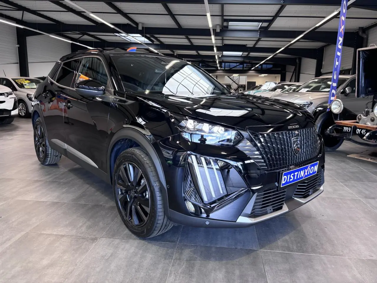 Peugeot 2008 noire vue 3/4 avant en intérieur, avec calandre noire distinctive et jantes alliage noires.