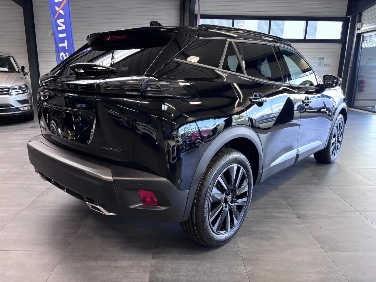 Vue 3/4 arrière droite d'un Peugeot 2008 noir brillant avec jantes alliage bi-ton et toit noir en showroom.