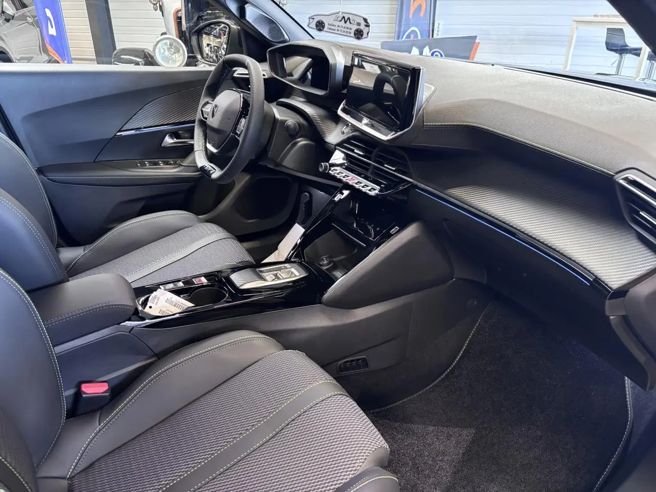 Intérieur avant droit du Peugeot 2008 1.2i Hybrid 2026, avec tableau de bord noir et écran tactile 10 pouces.