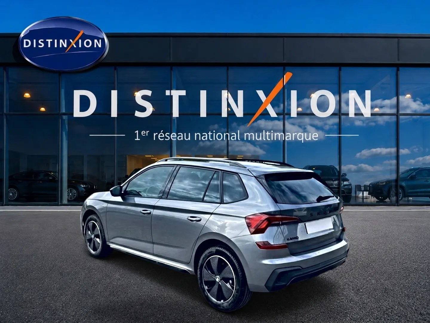 Vue 3/4 arrière droite d’un Skoda Kamiq gris graphite avec jantes alu noires devant une vitrine Distinxion.