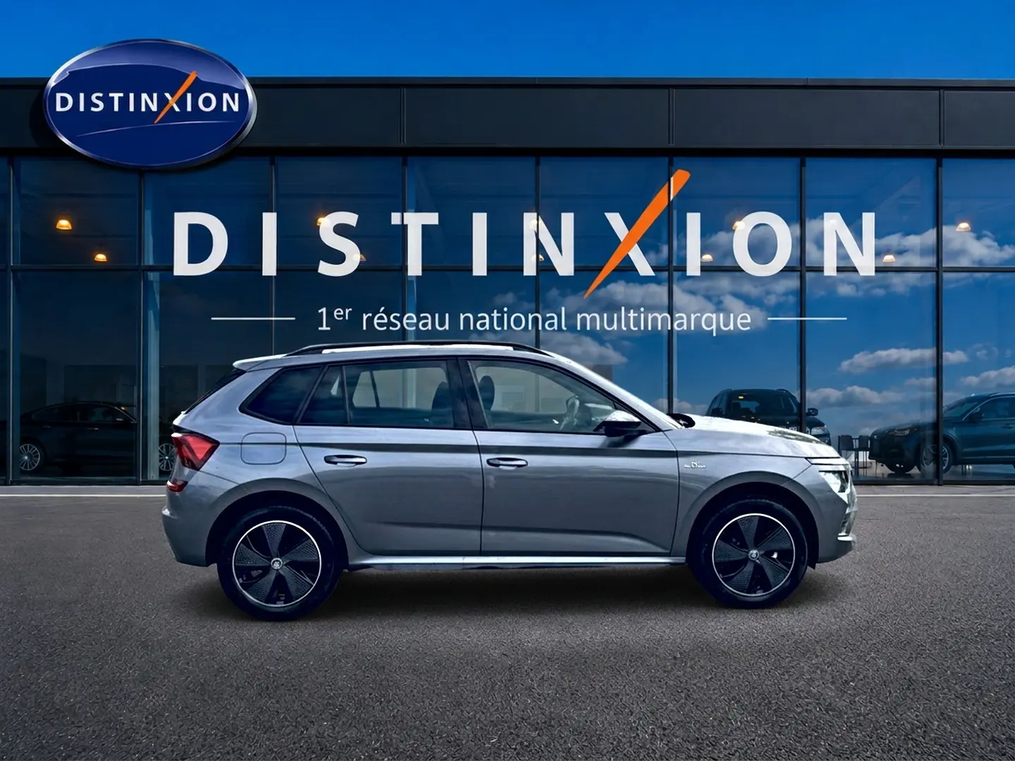Profil droit du Skoda Kamiq gris graphite 2026 avec jantes alu noires et toit panoramique en verre visible.
