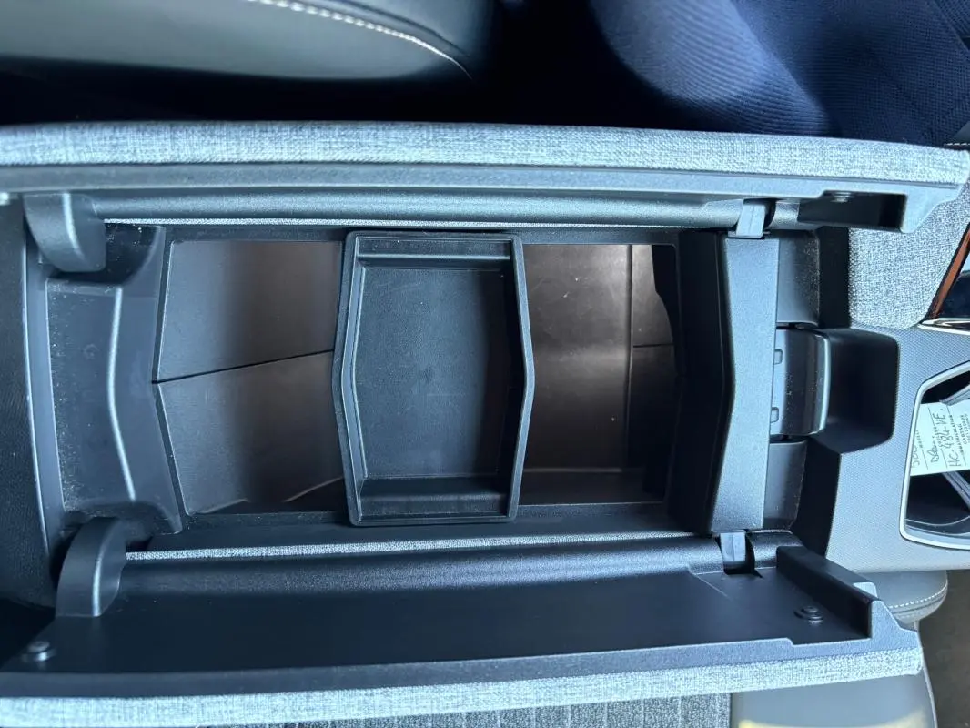 Vue plongeante sur le rangement central ouvert du Peugeot 5008 bleu foncé, version Hybrid 145 ch e-DCS6 Allure 2025.