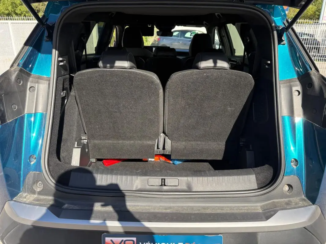 Coffre ouvert vu de l'arrière d'un Peugeot 5008 Hybrid bleu foncé 2025, avec sièges arrière relevés.