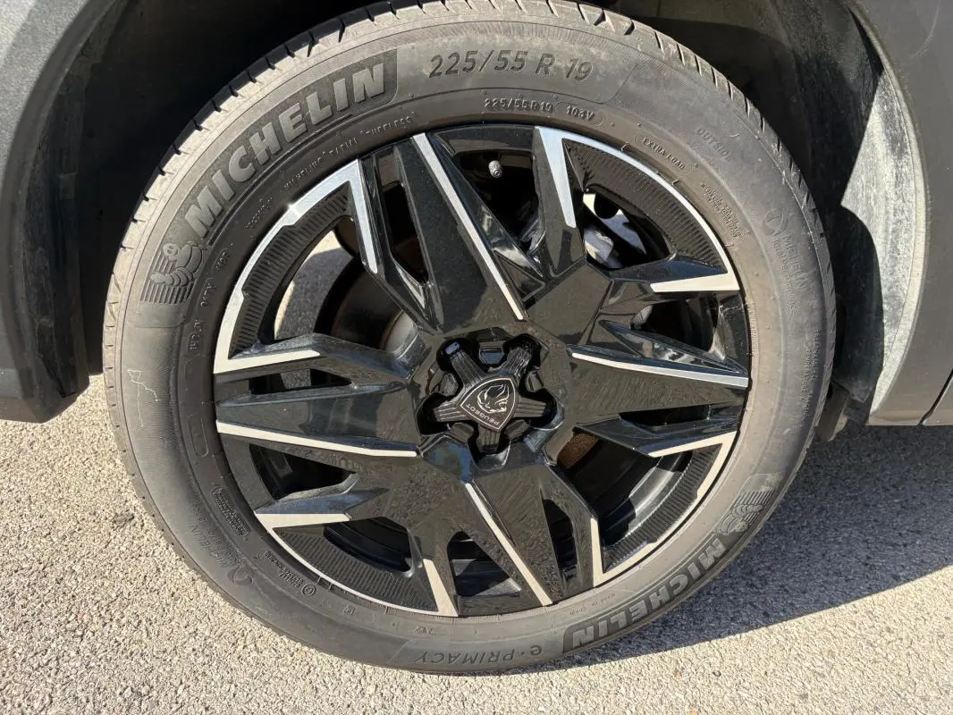 Gros plan sur la roue avant droite du Peugeot 5008 bleu foncé 2025, jante noire à motifs géométriques distinctifs.