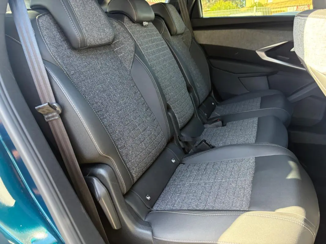 Vue latérale droite des sièges arrière en tissu gris et cuir noir du Peugeot 5008 Hybrid 2025 bleu foncé, finition Allure.