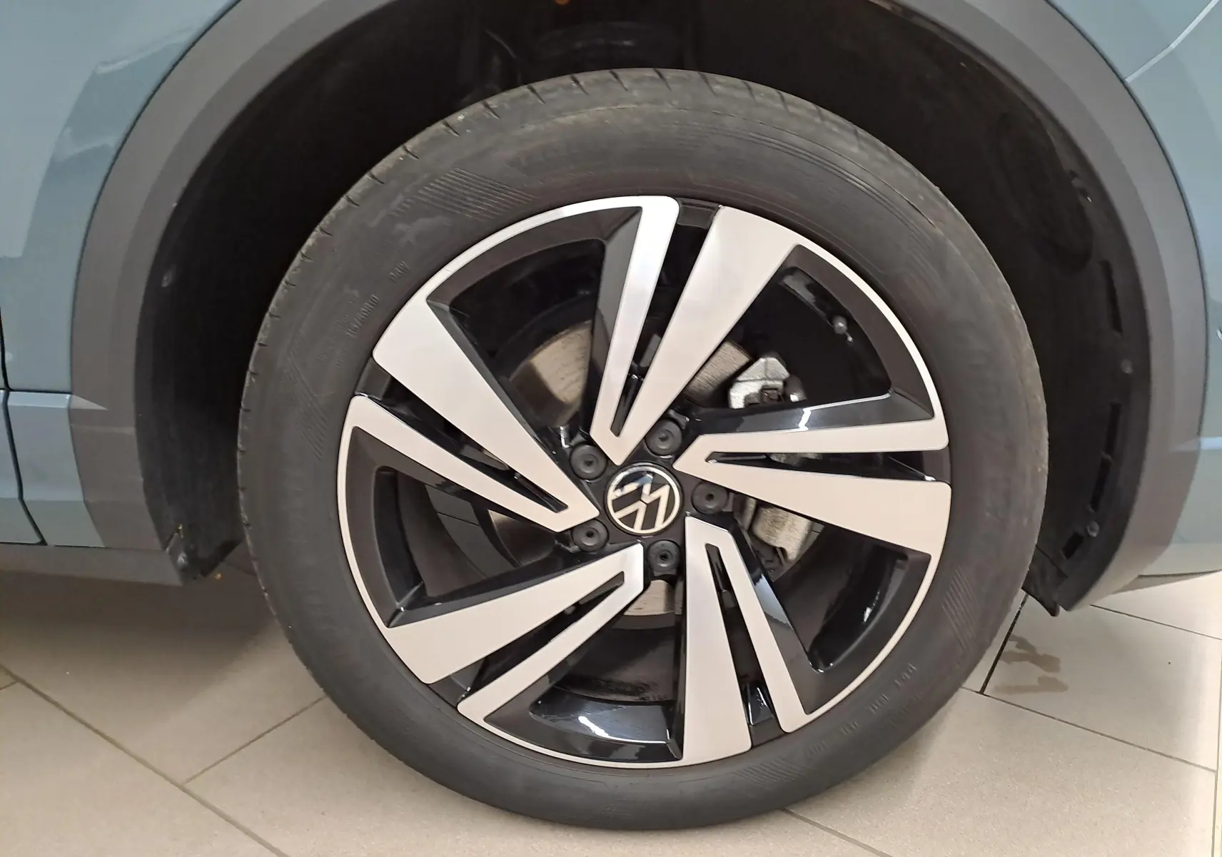 Gros plan sur la roue avant droite du Volkswagen T-Roc bleu pétrole, mettant en valeur la jante R-Line au design moderne.