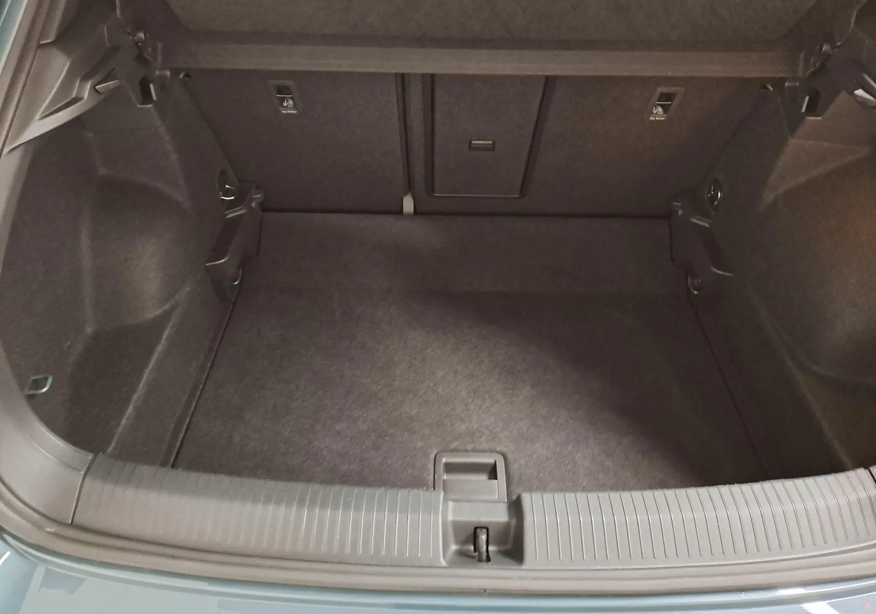 Coffre ouvert du Volkswagen T-Roc bleu pétrole, vue plongeante sur l'espace de chargement vide et ses finitions internes.