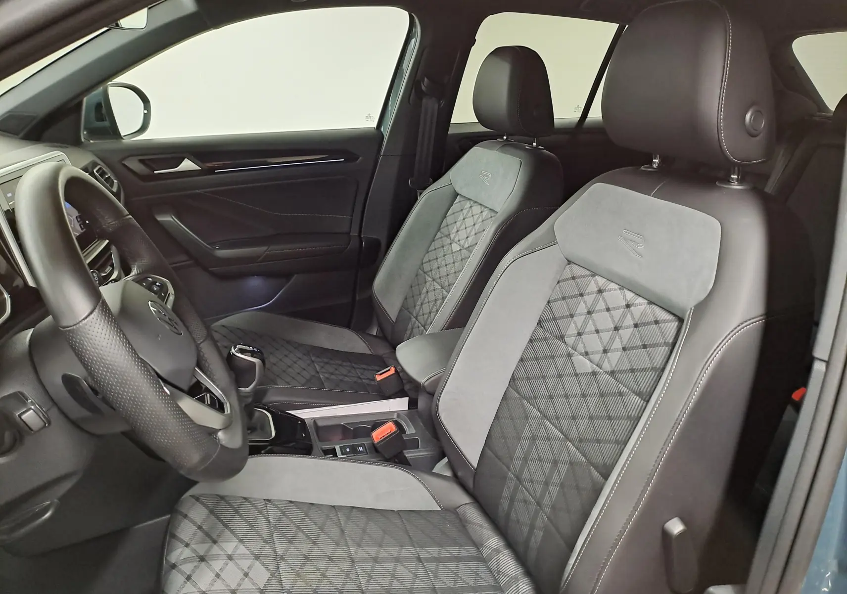 Vue intérieure côté conducteur du Volkswagen T-Roc 1.5 TSI R-Line avec sièges en tissu et cuir gris, volant multifonction.