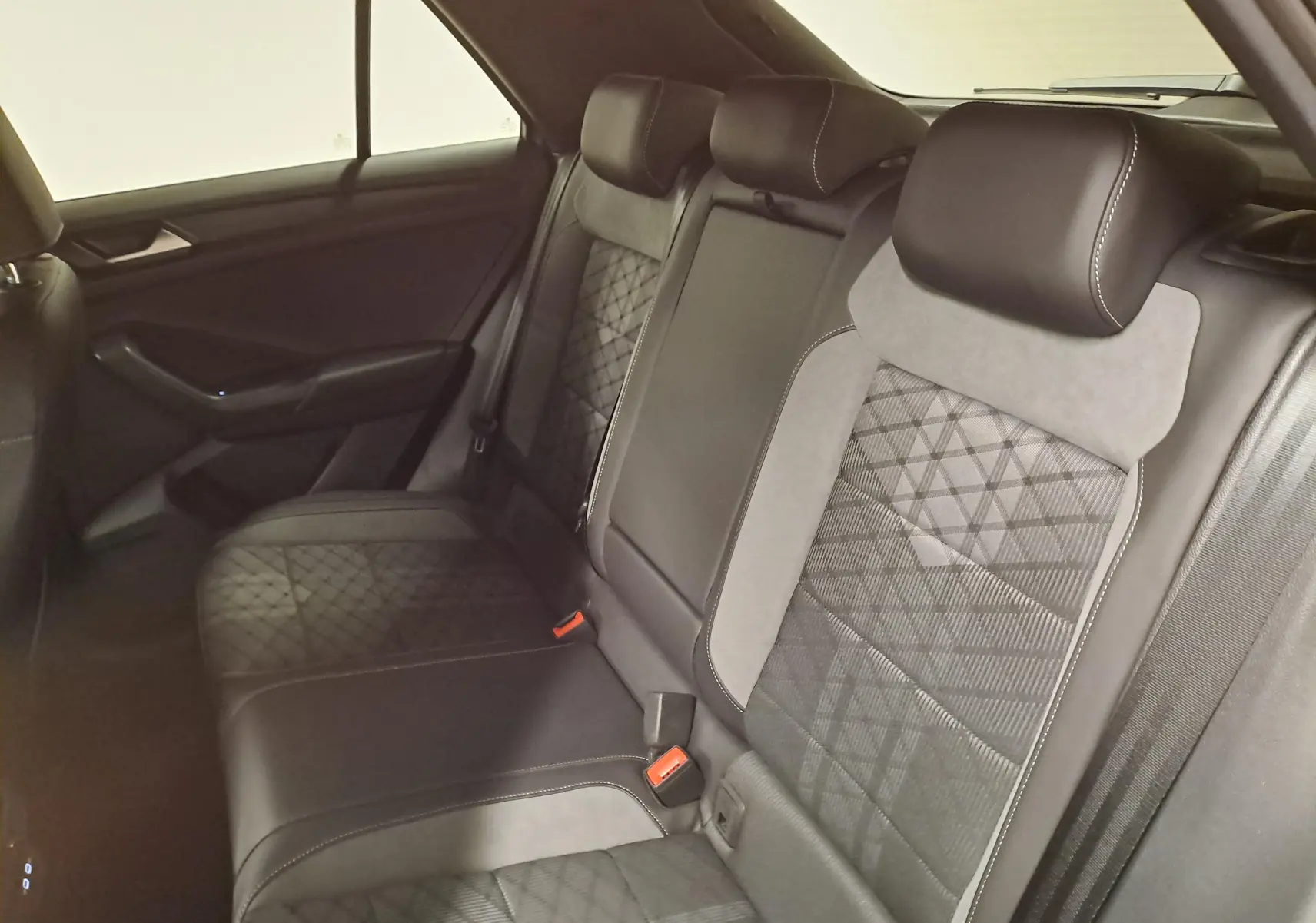 Vue intérieure des sièges arrière du Volkswagen T-Roc 1.5 TSI 150 DSG7 R-Line Edition, revêtement noir avec surpiqûres grises.