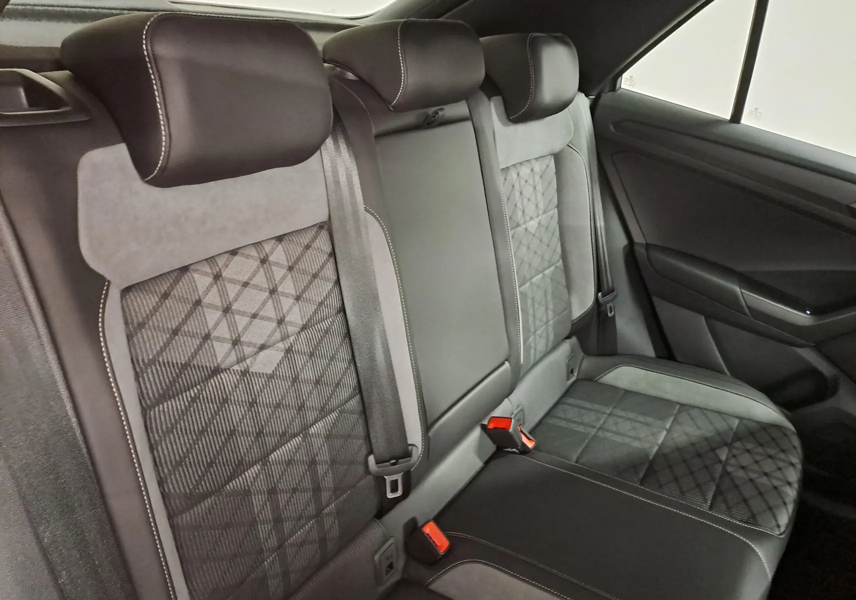 Vue intérieure du siège arrière droit du Volkswagen T-Roc 2025, avec sellerie tissu et cuir noir à motifs géométriques.