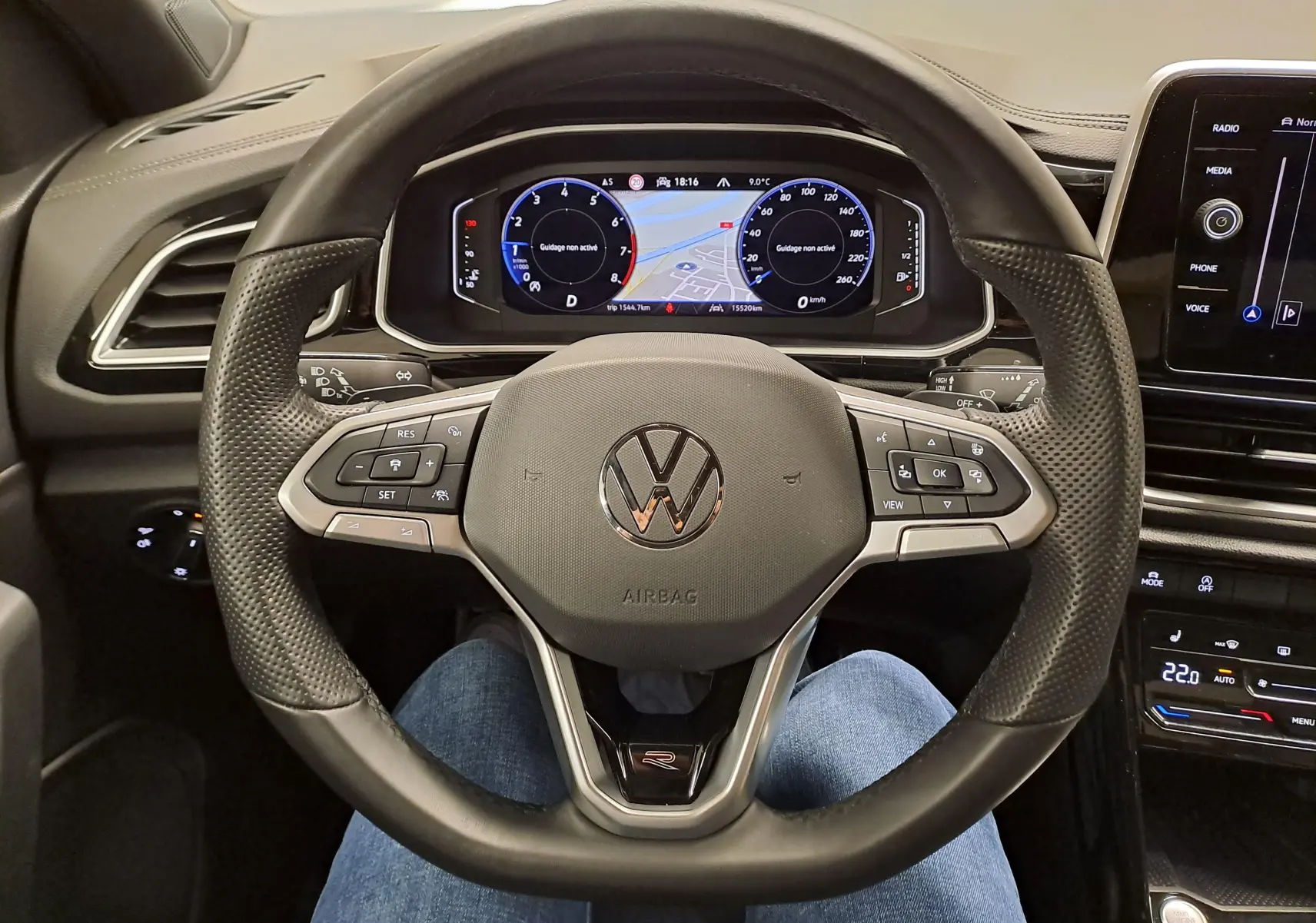 Vue intérieure centrée sur le volant multifonction du Volkswagen T-Roc 2025, avec tableau de bord numérique et finitions R-Line.