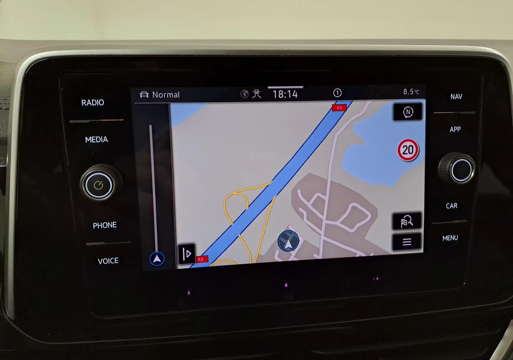 Écran tactile central du Volkswagen T-Roc 1.5 TSI bleu pétrole, affichant la navigation avec carte et options autour.