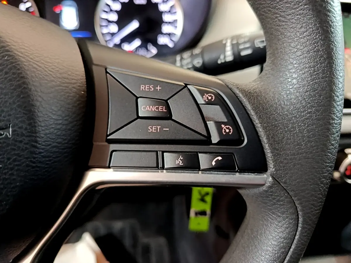 Gros plan sur le côté droit du volant noir de la Nissan Micra 2020 avec commandes de régulateur de vitesse et téléphone.