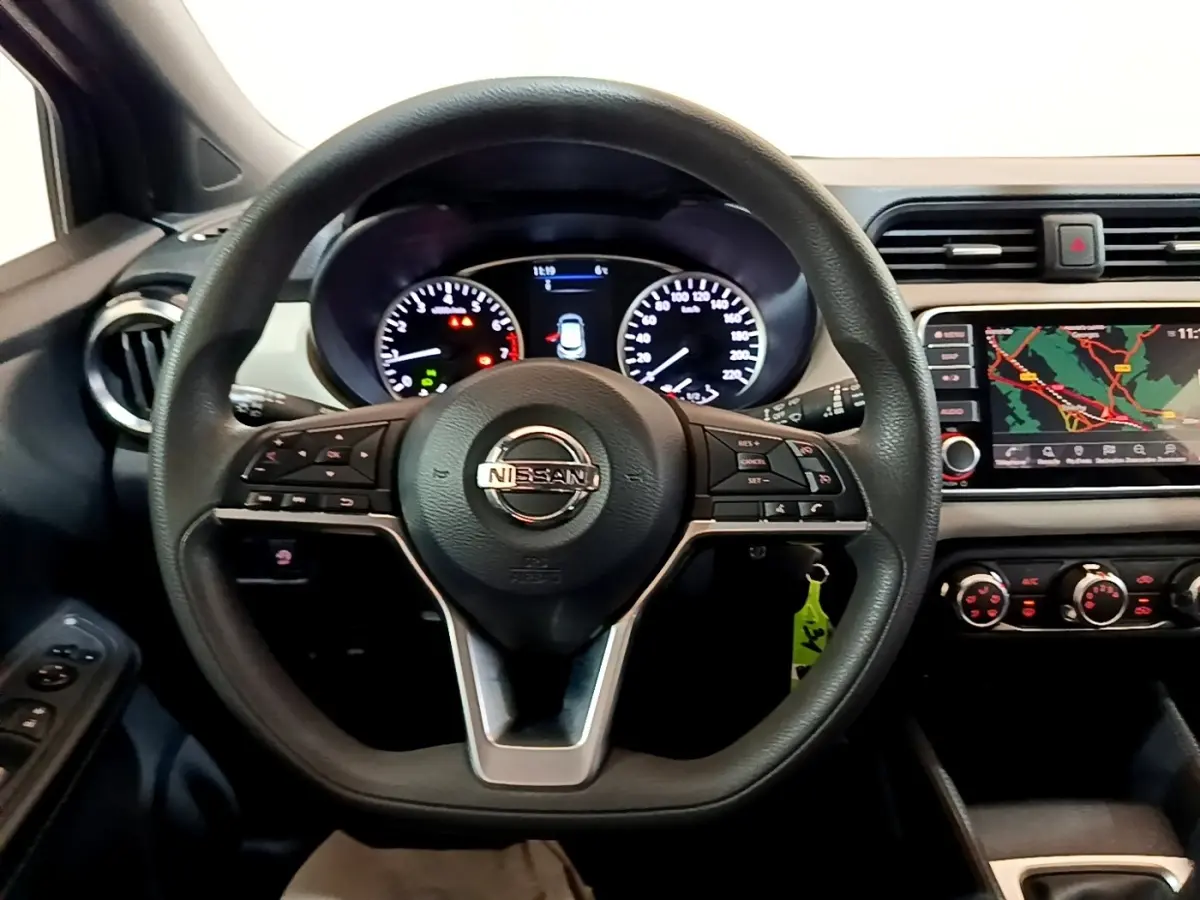 Vue intérieure centrée sur le volant multifonctions noir d’une Nissan Micra 2020 avec tableau de bord et écran tactile de navigation.