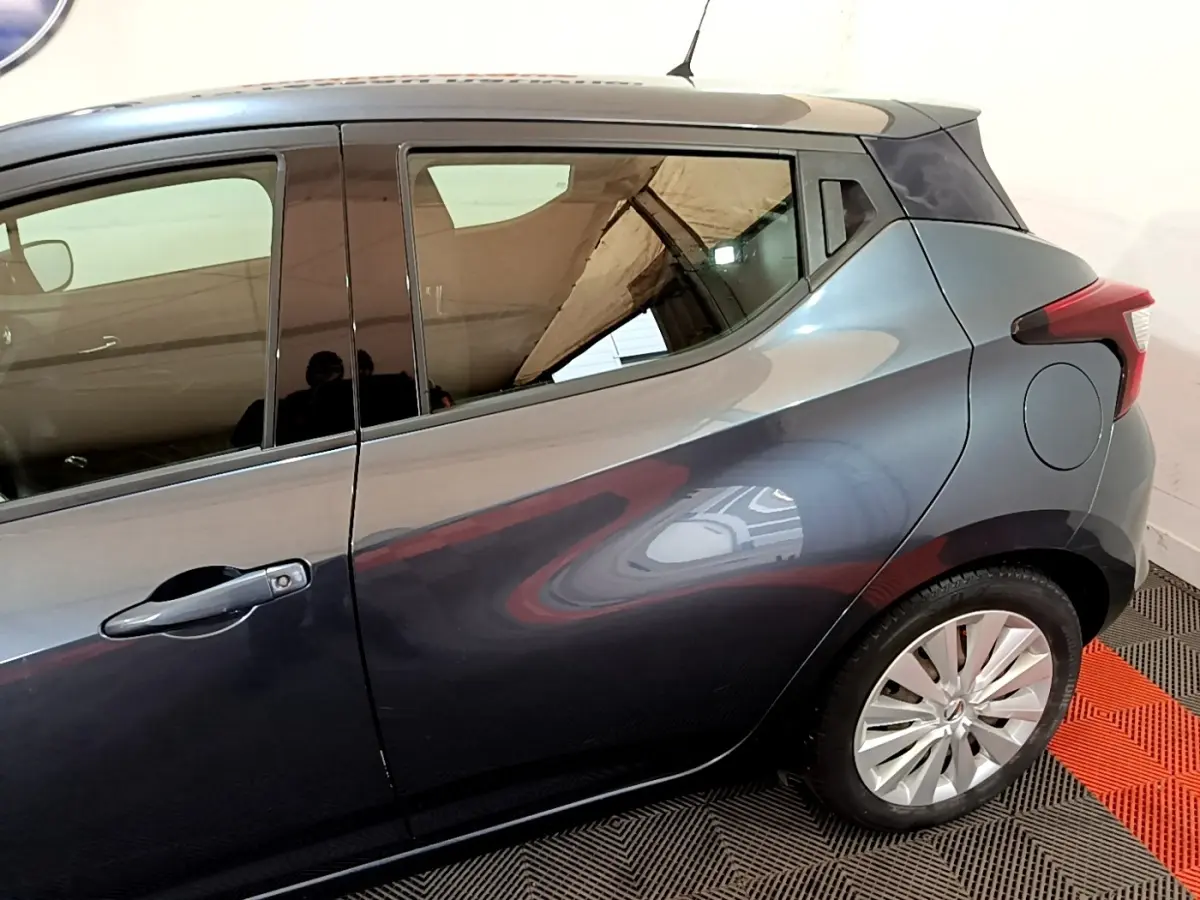 Vue latérale côté droit d'une Nissan Micra gris foncé, mettant en valeur la ligne fluide et la jante alliage arrière.