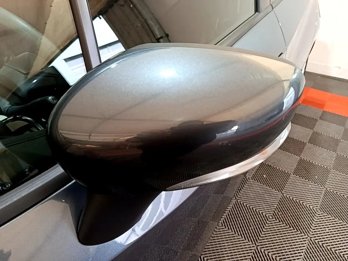 Gros plan sur le rétroviseur droit gris foncé de la Nissan Micra IG-T 100 Business Edition, avec reflet et partie de la portière visible.