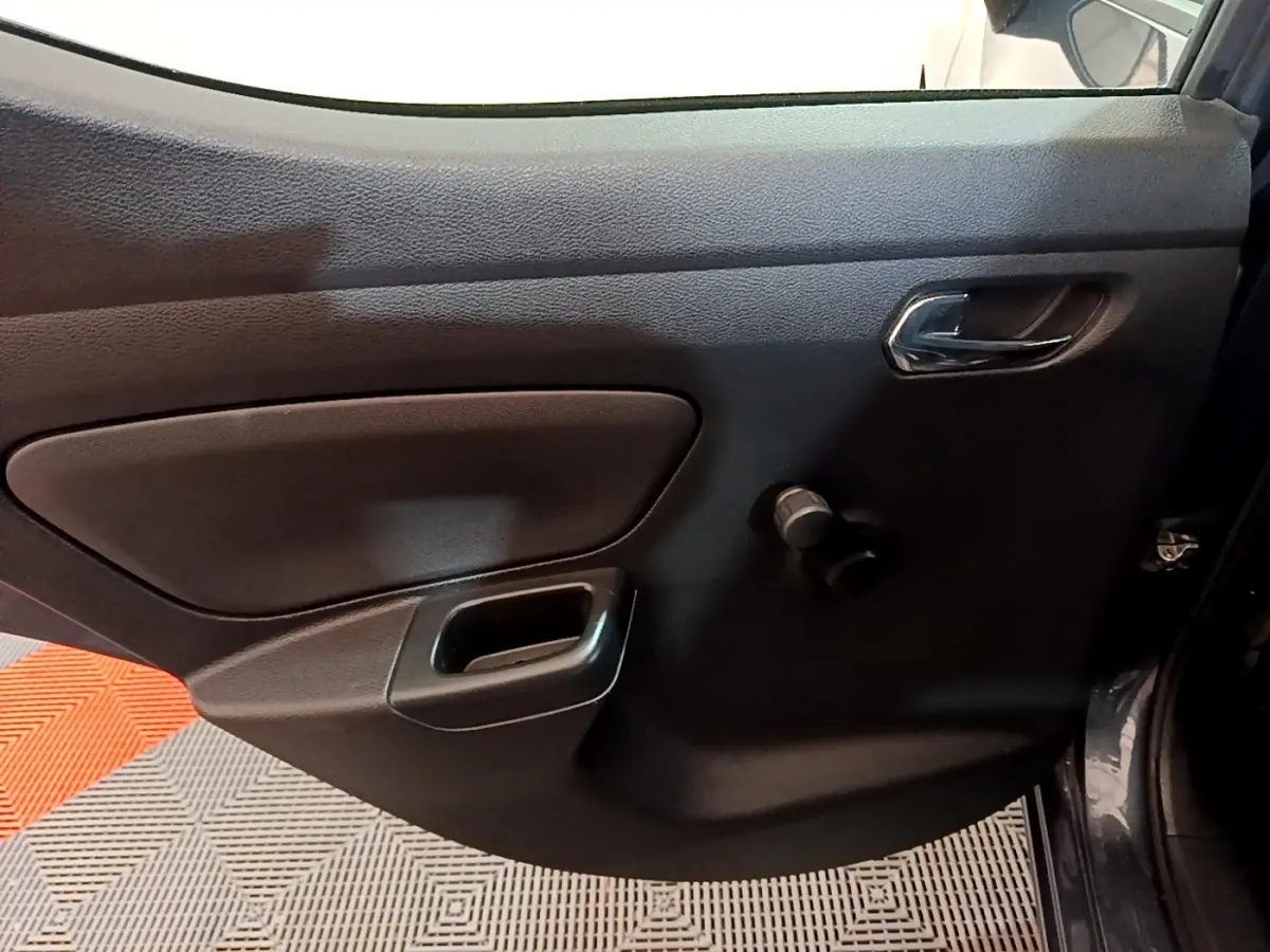 Vue rapprochée de la porte intérieure côté droit de la Nissan Micra gris foncé avec poignée chromée et manivelle de vitre.