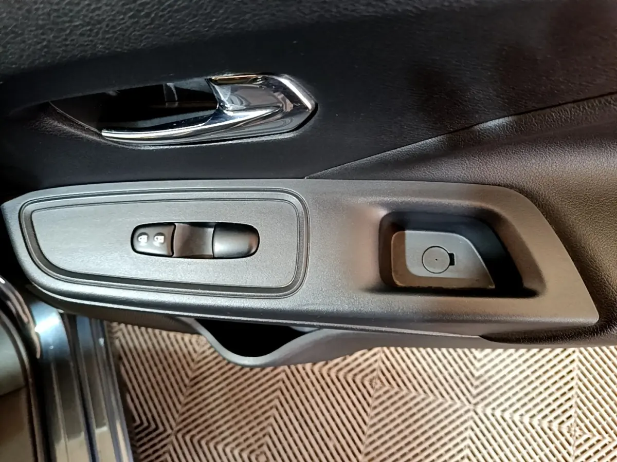 Gros plan sur la poignée intérieure et les commandes de verrouillage de porte côté conducteur d'une Nissan Micra gris foncé.