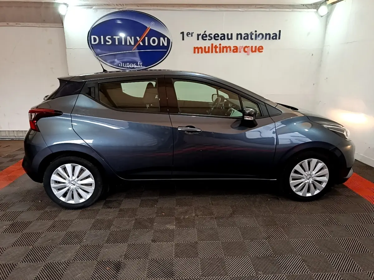 Profil droit d'une Nissan Micra IG-T 100 Business Edition gris foncé, en intérieur sur sol carrelé noir et rouge.