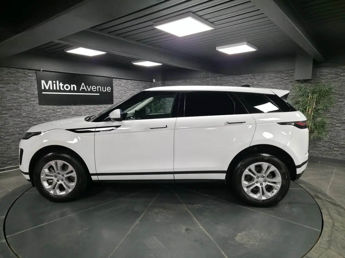 Range Rover Evoque blanc vu de profil côté gauche, avec jantes 18 pouces et toit noir contrasté.
