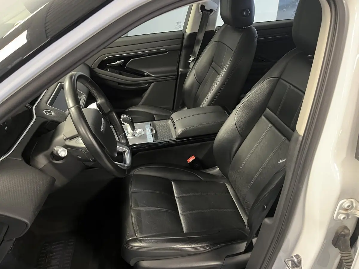 Vue intérieure côté conducteur du Range Rover Evoque blanc 2020, sièges cuir noirs et console centrale moderne.